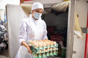 Woman carrying eggs, wearing a white coat
