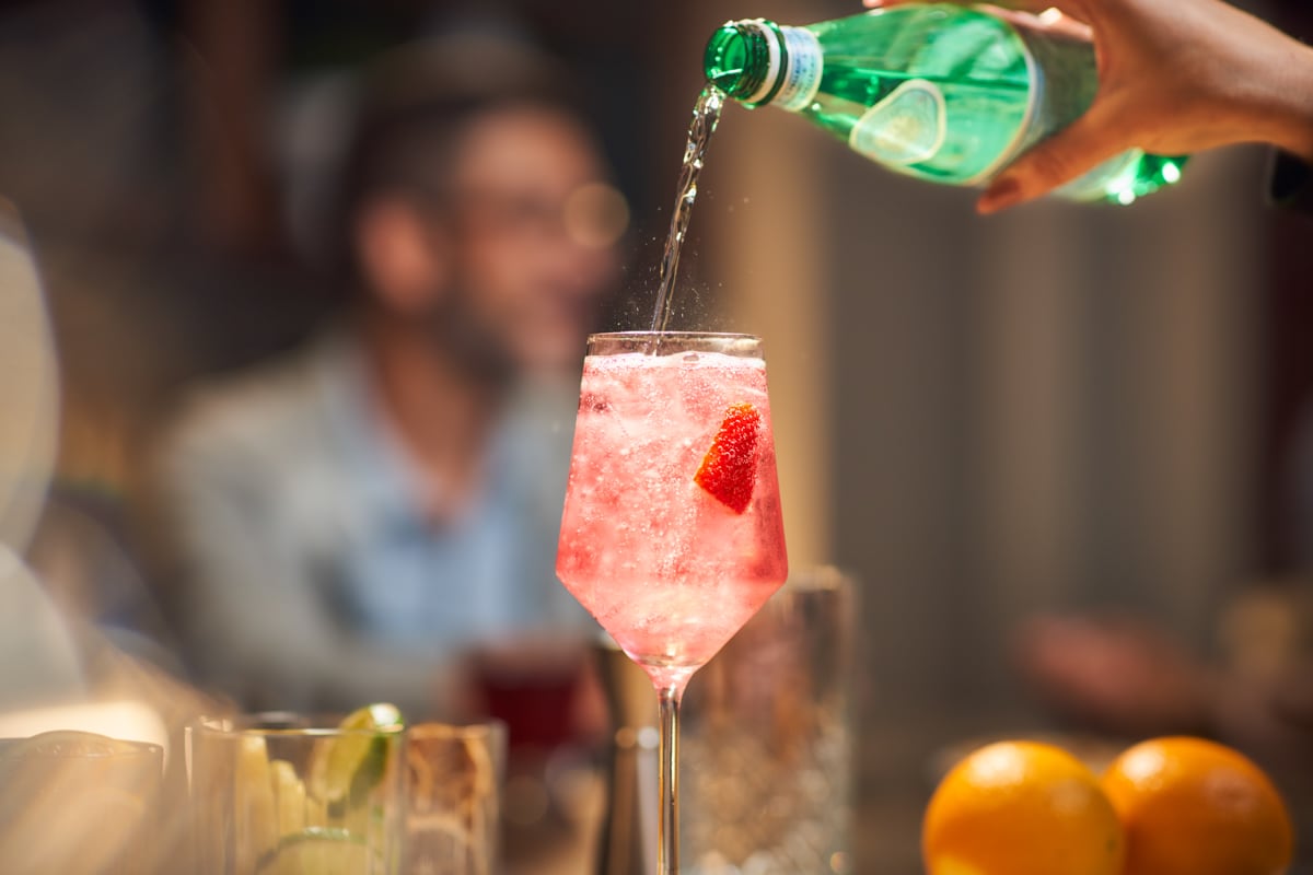 Pouring a strawberry drink from bottle to glass.