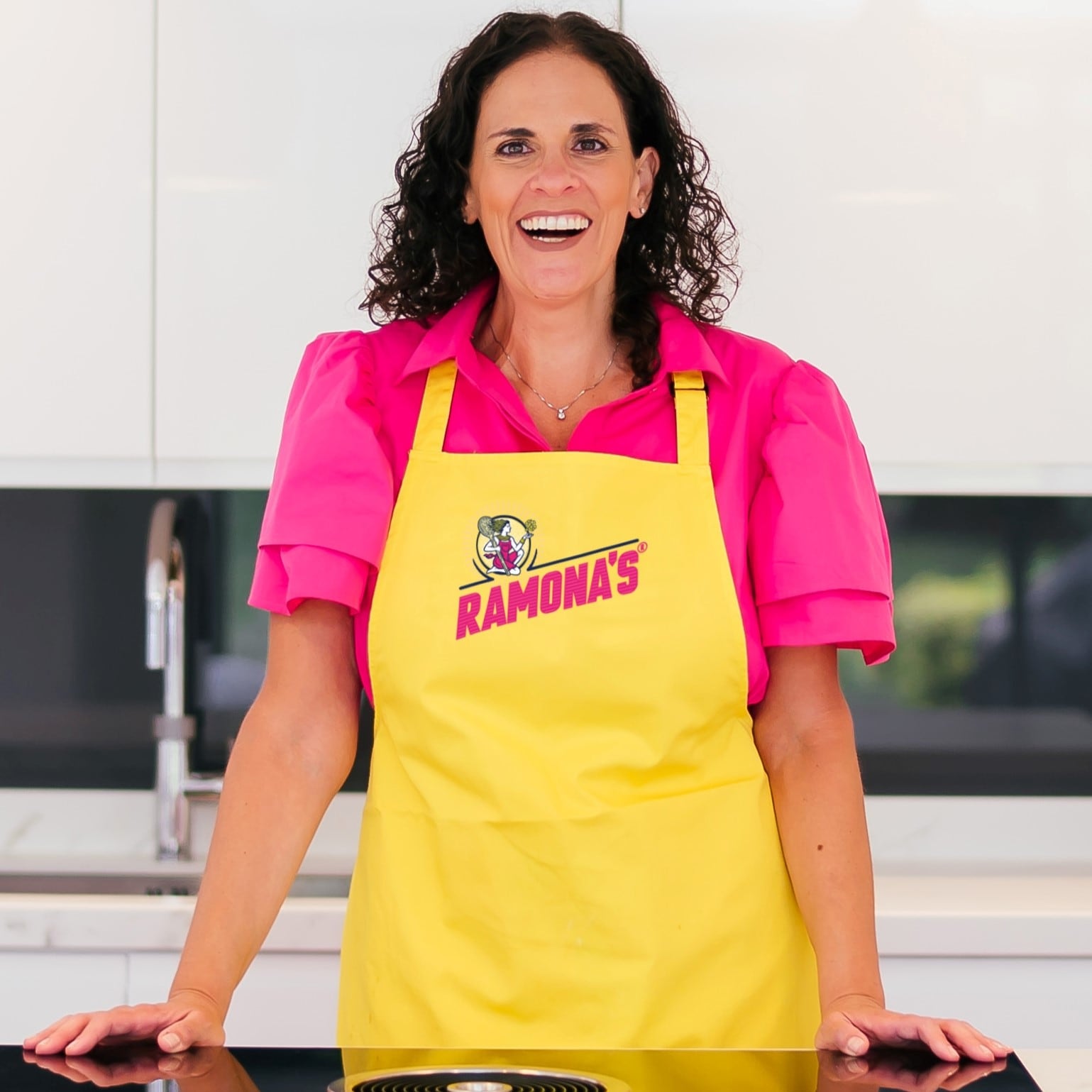 Ramona Hazan founder of Ramona's in a branded apron