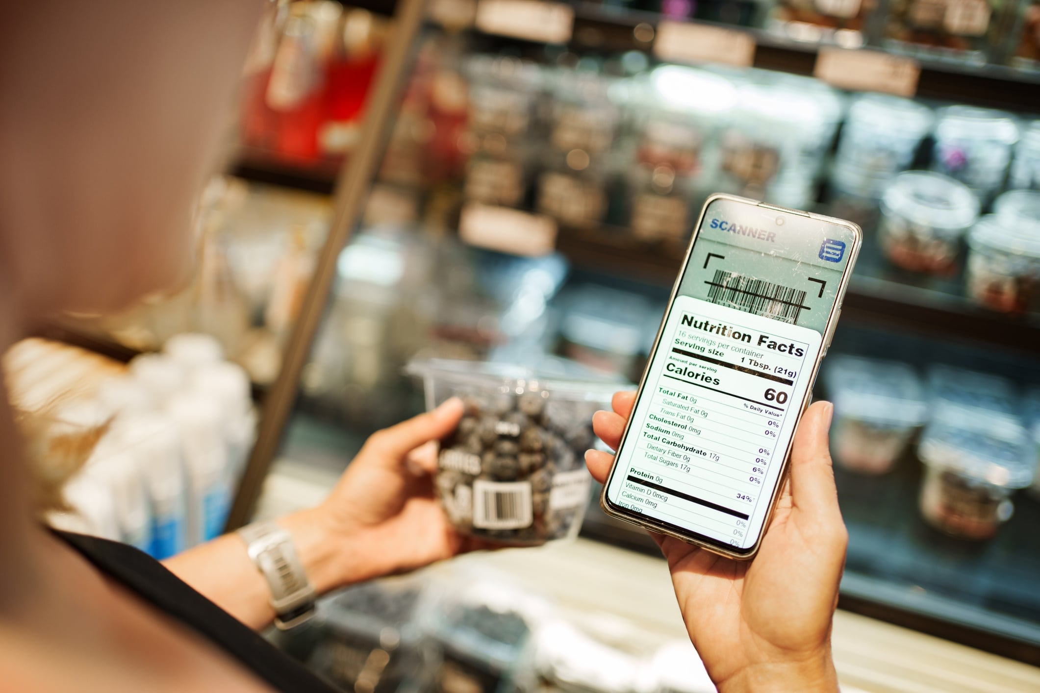 Consumer holding a snack with ingredient label in view on cellphone