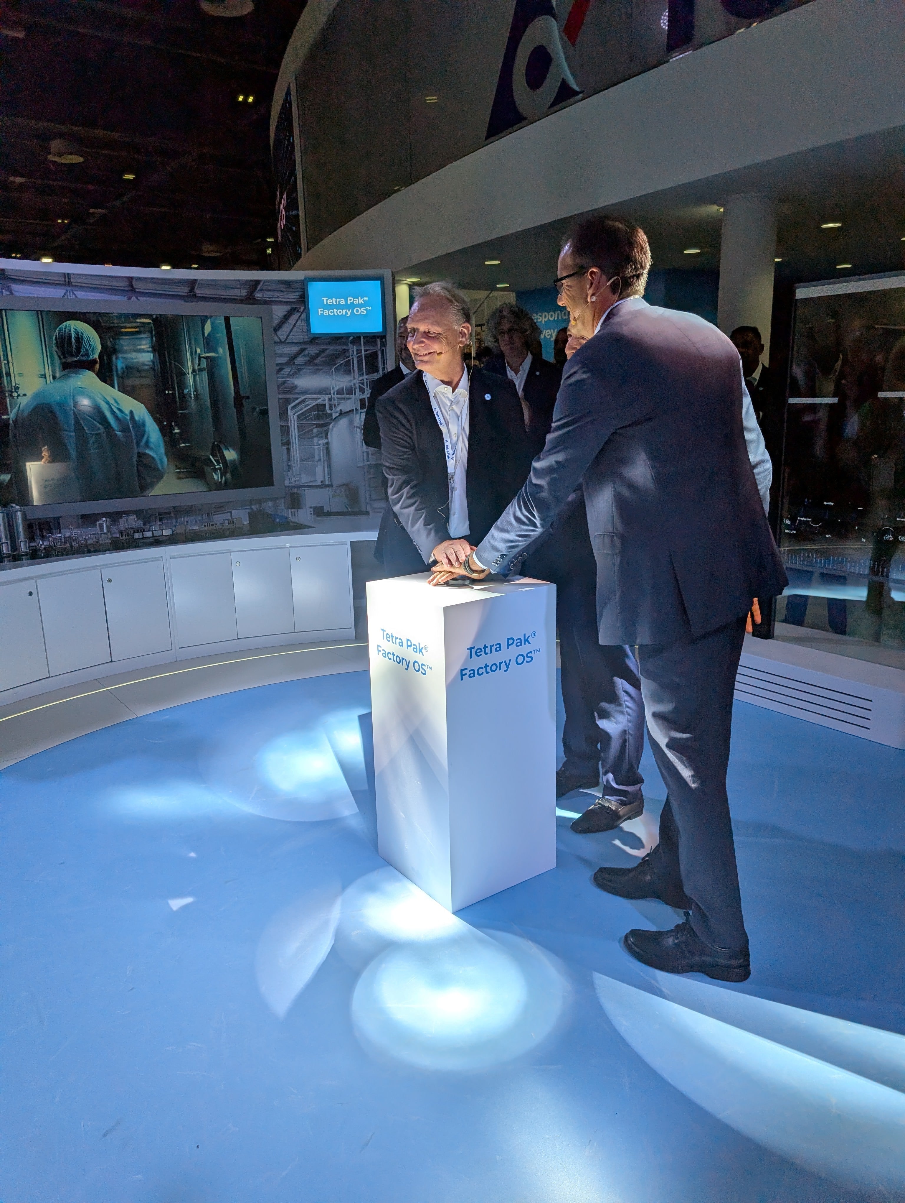 Charles Brand and Sean Sims pressing a button at the launch of Tetra Pak Factory OS at Gulfood Manufacturing 2025, situated at the company's booth.