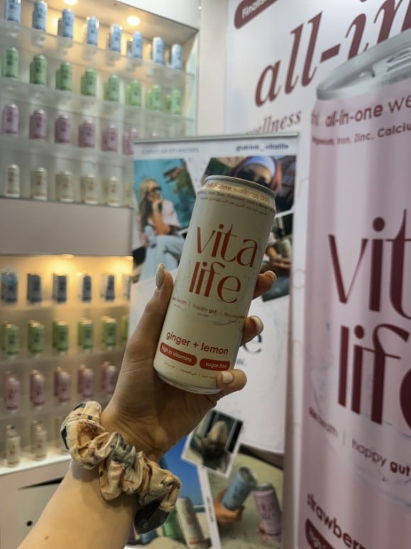 A hand holding up a can of Vitalife.