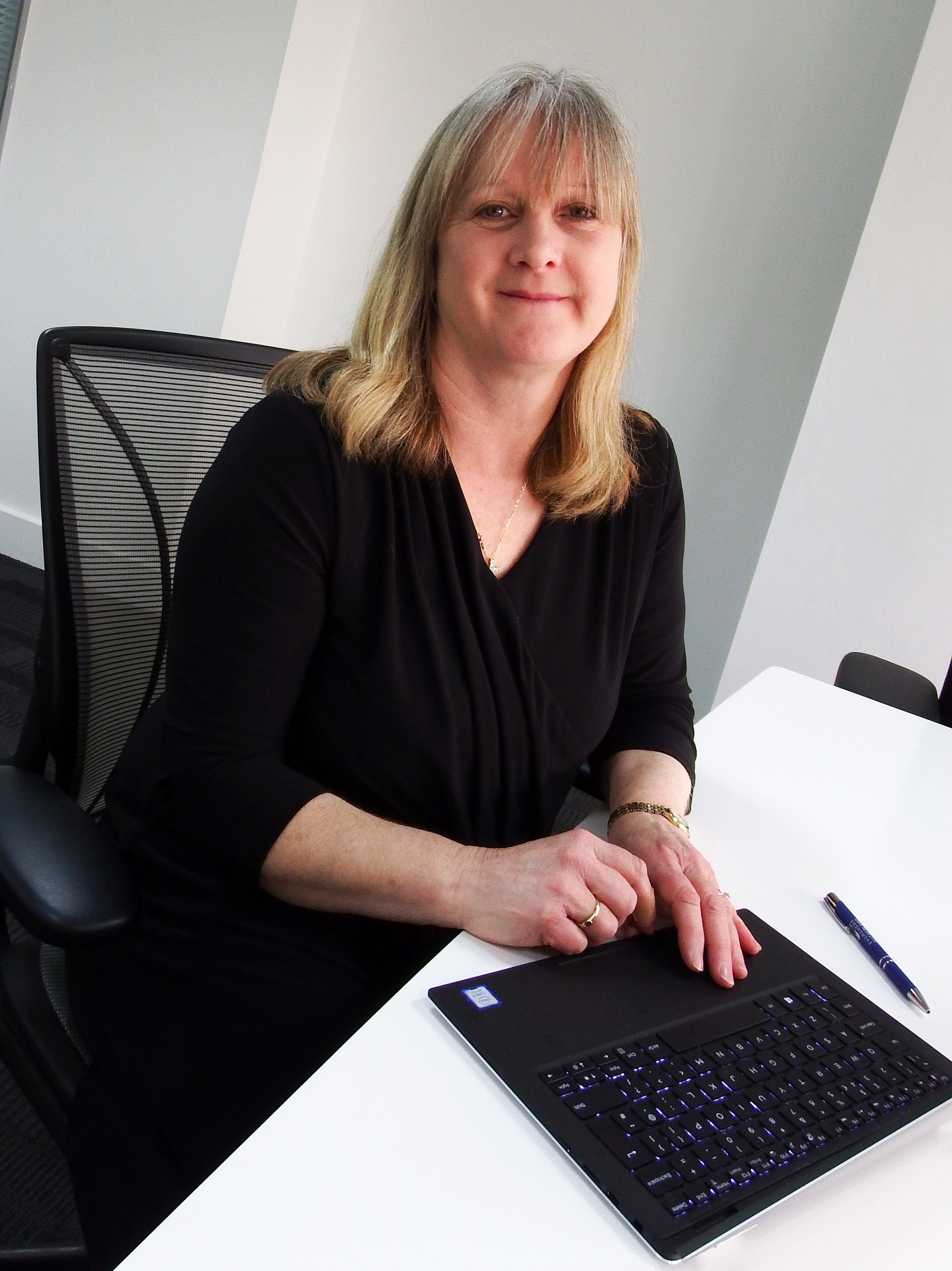 Helen Sisson, technical director, 2 Sisters, sitting at desk with laptop.