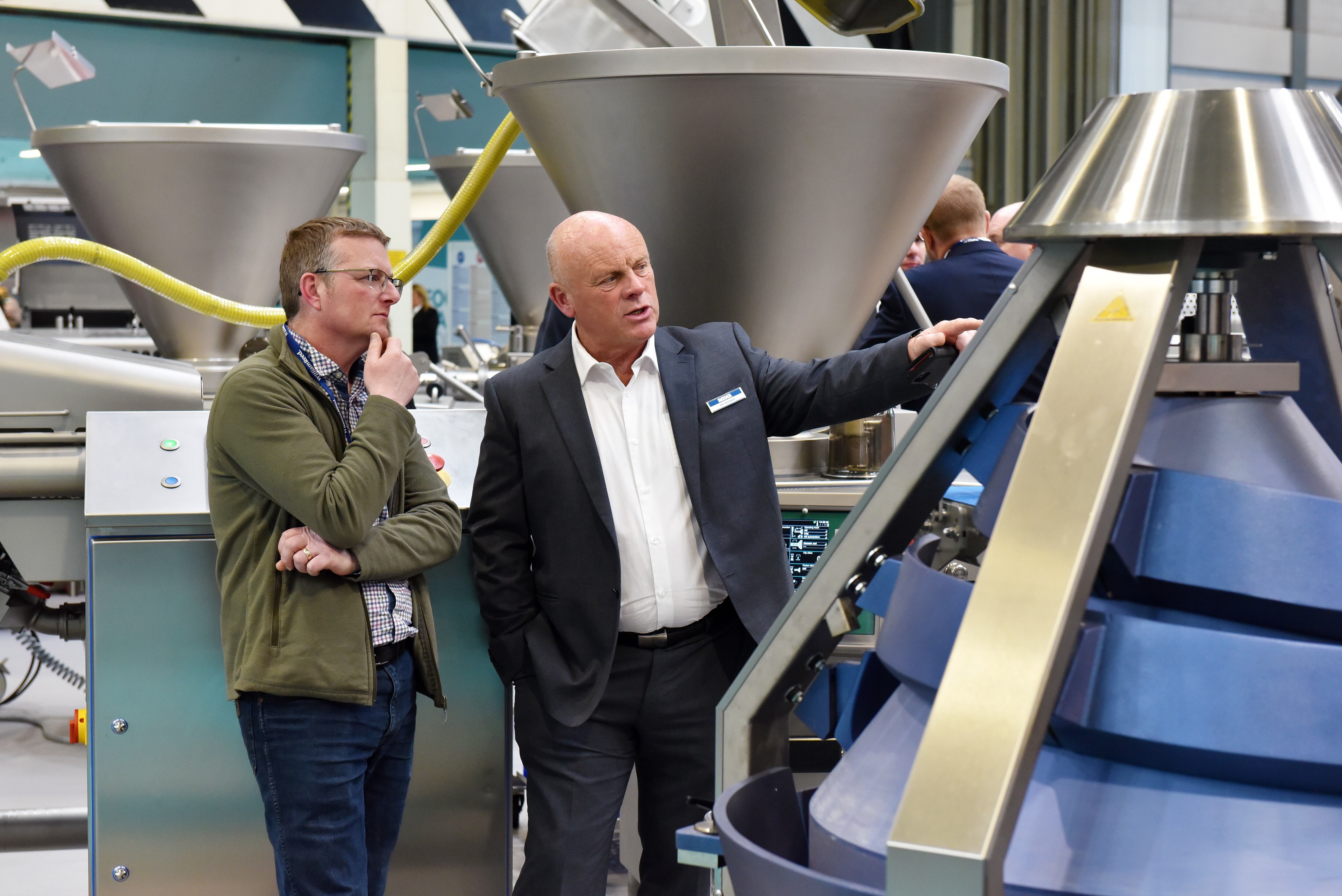 Two men looking at food production machinery.