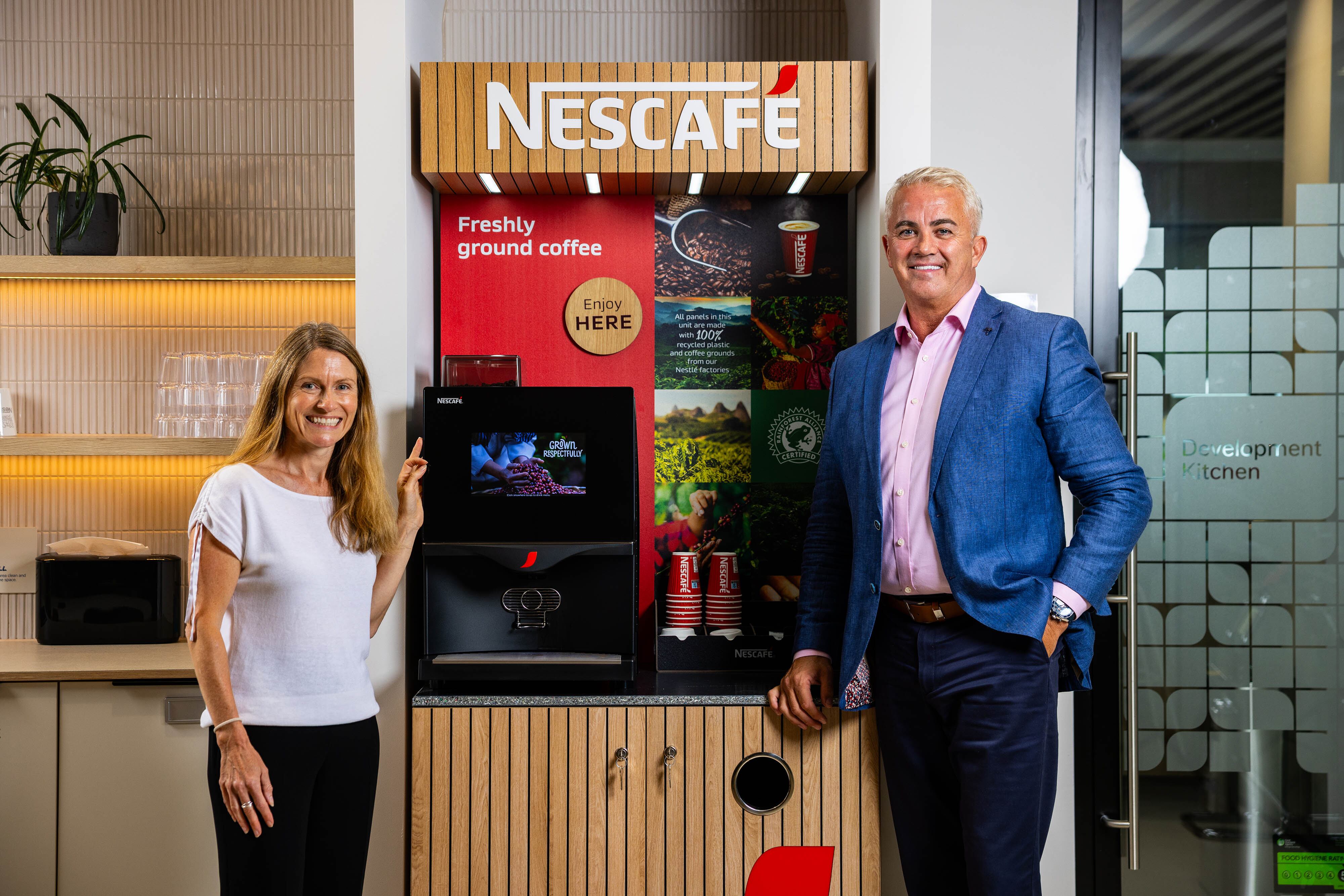 Two people standing with new Nestle Nescafe sustainable furniture.