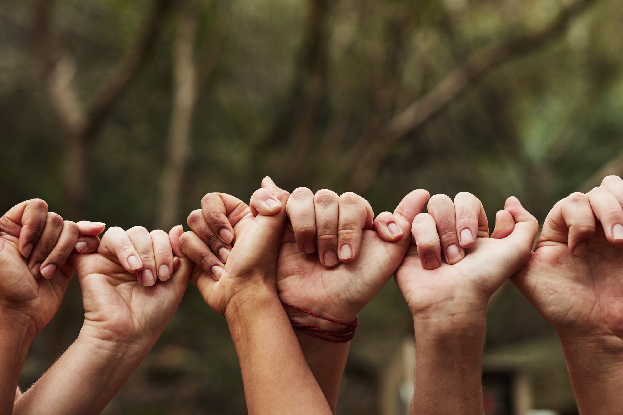 Cropped shot of a group of unrecognisable people linking fingers out in nature