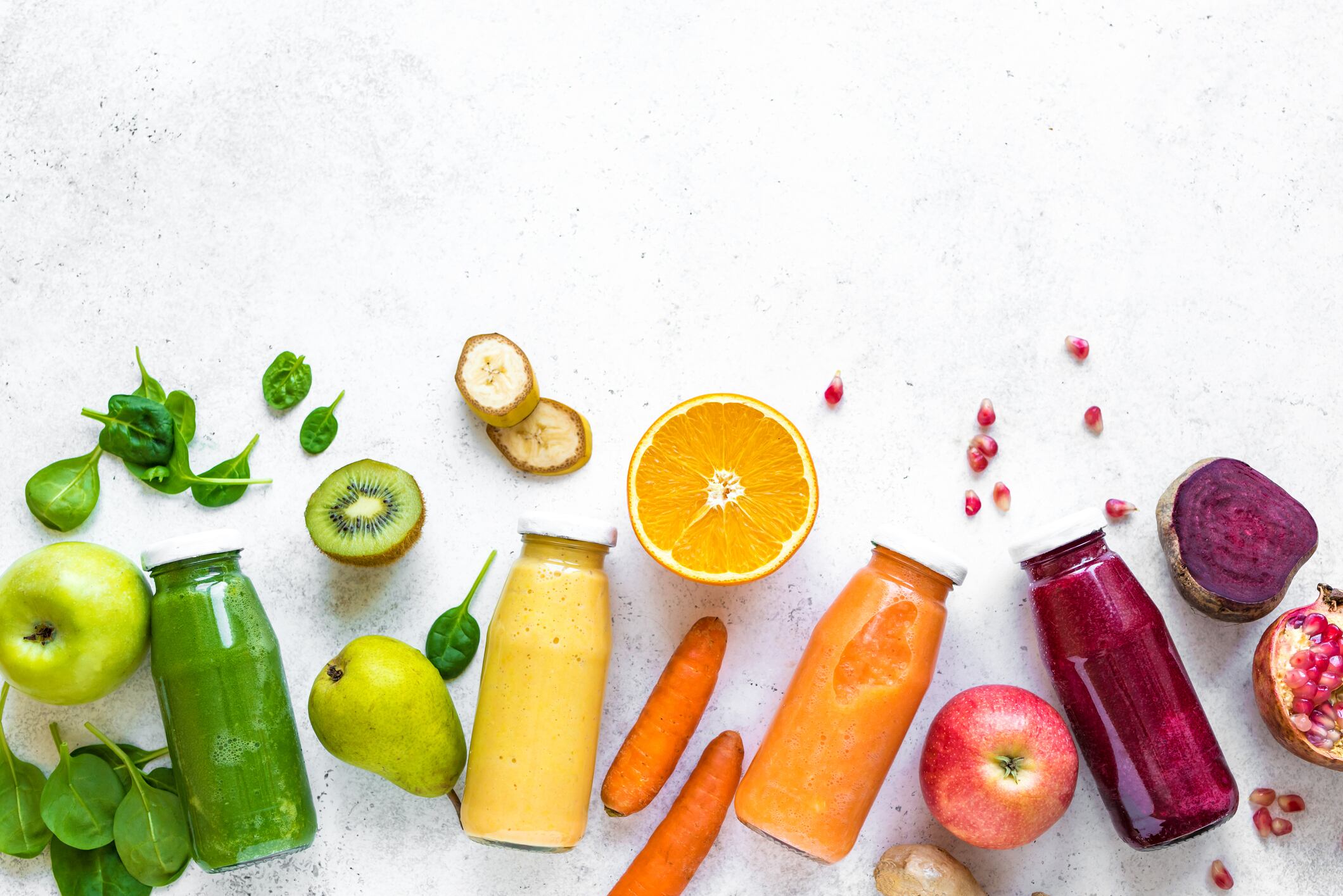 Various smoothies or juices in bottles and ingredients on white, healthy diet detox vegan clean food concept, top view, copy space.