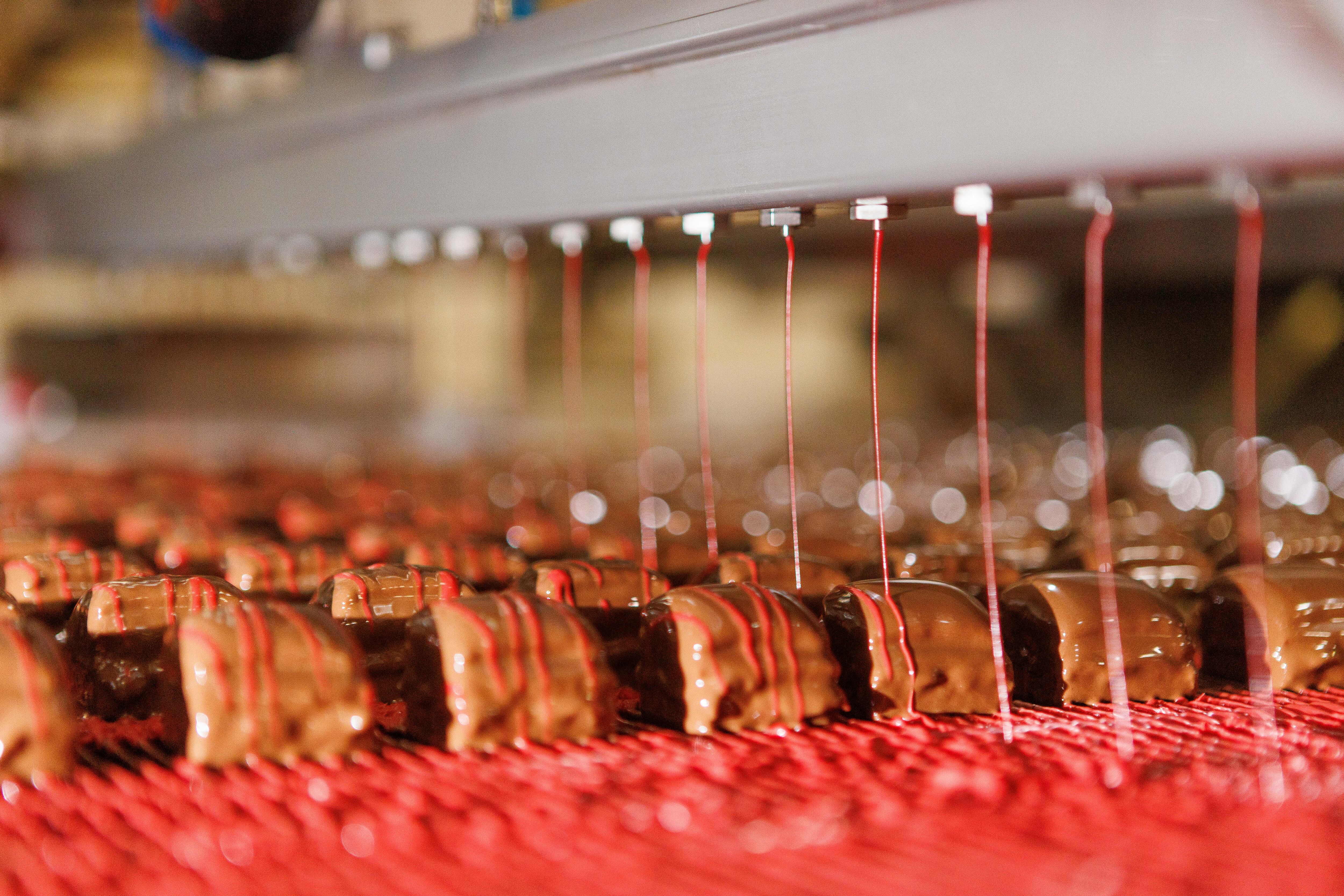 Cakes being drizzled on product line.