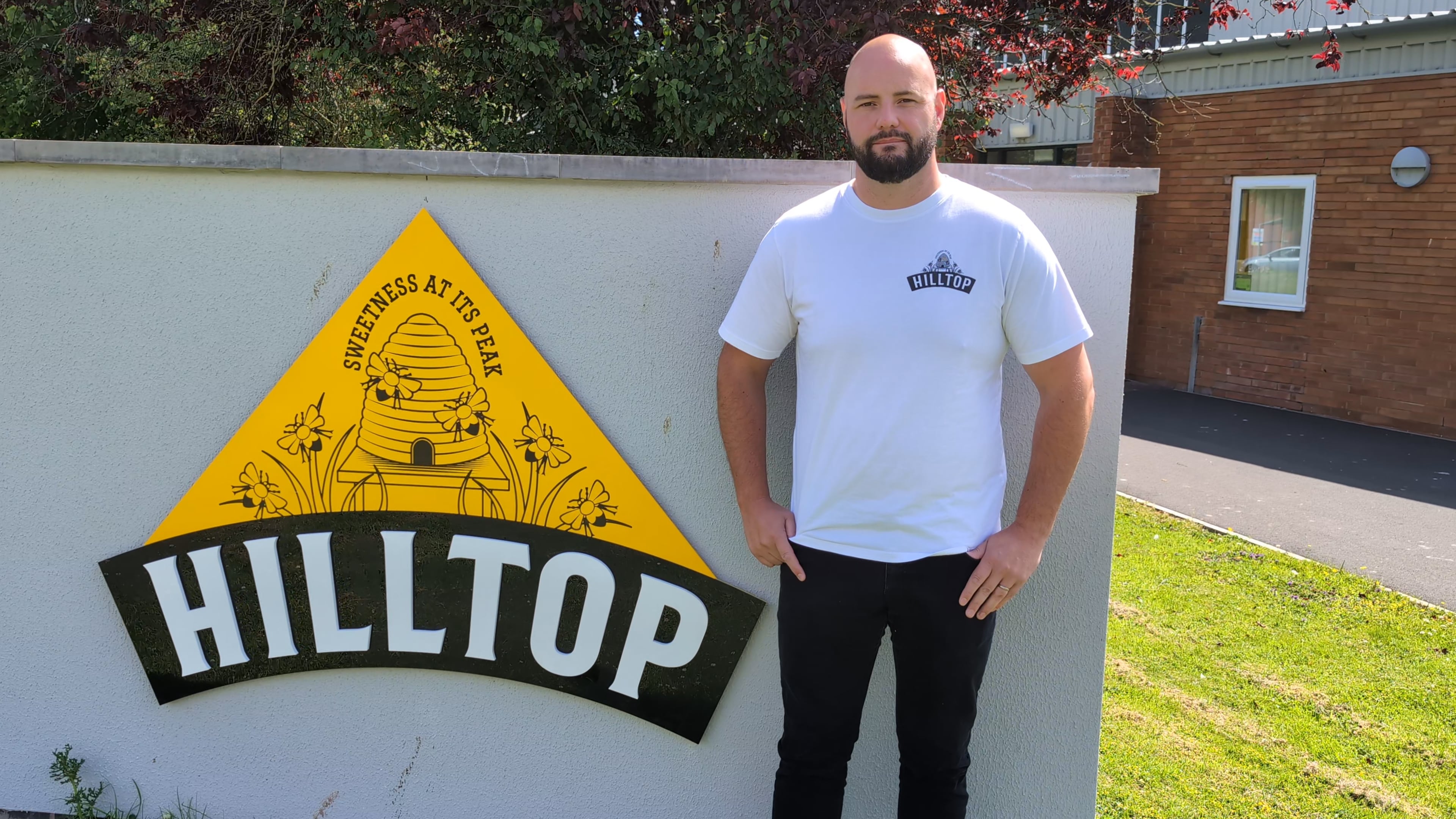 Scott Davies standing in front of a sign that reads Hilltop Honey.