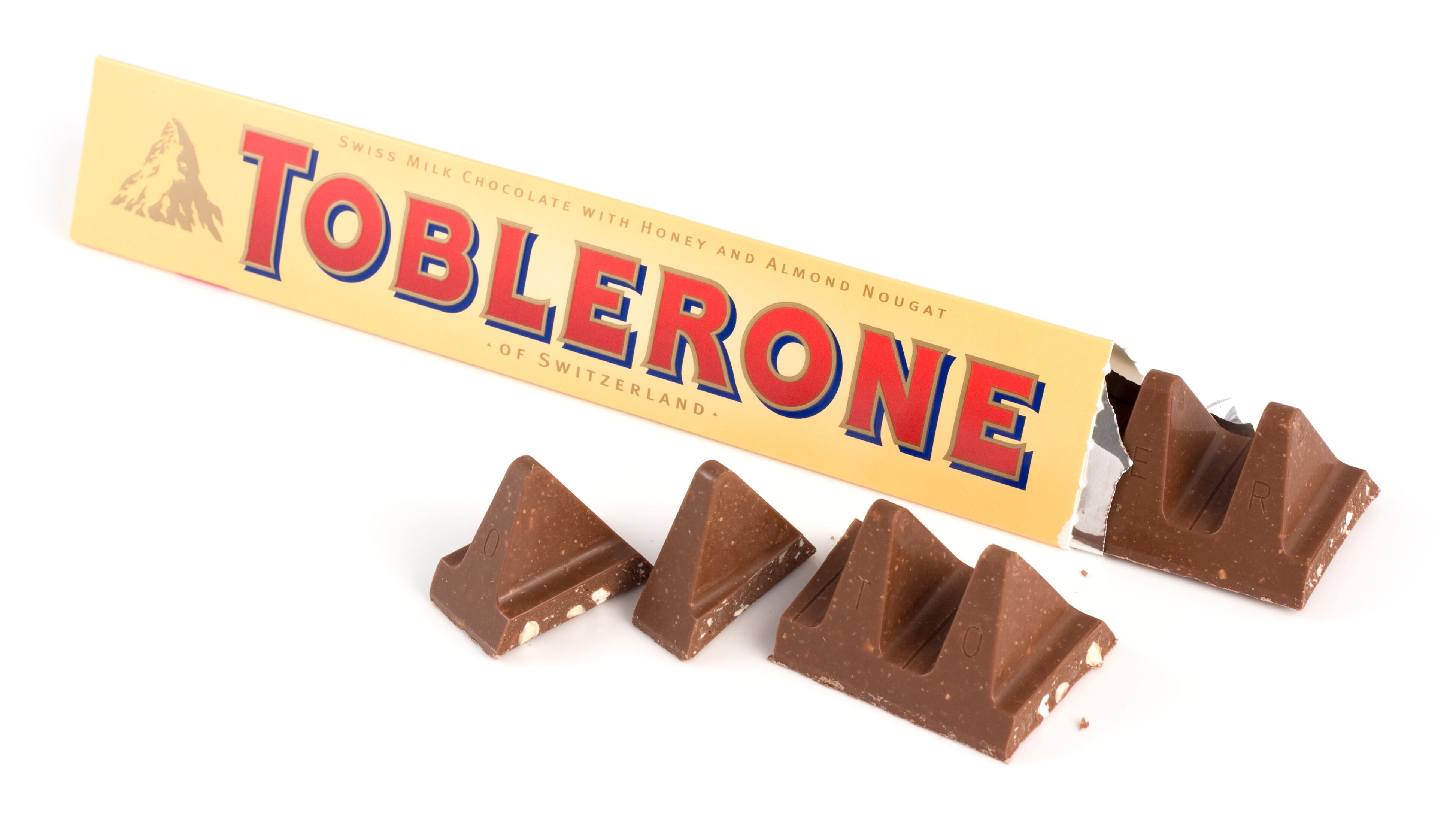 "St Ives, England - November 19, 2012: A bar of Toblerone - Swiss milk chocolate with honey and almond nougat on a white background. Toblerone is produced by the multinational food and beverage company Kraft foods."