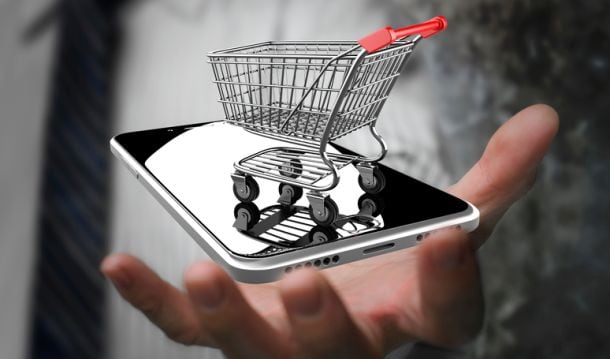 A mobile phone hovering over a hand, with a tiny trolley on top.