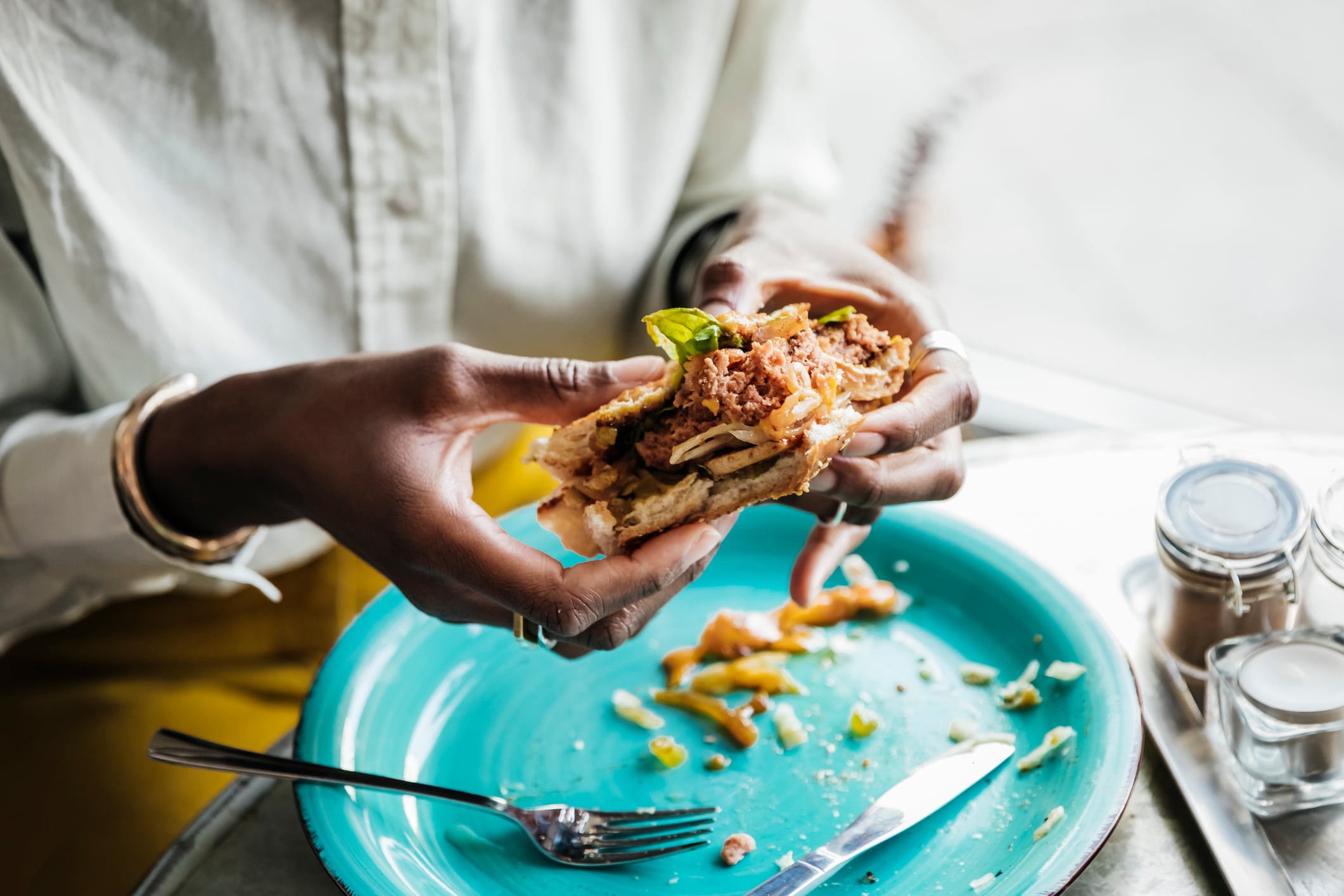 A woman enjoying eating a tastly looking vegan burger in a cafe.