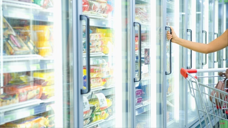 Person opening fridge door in supermarket.