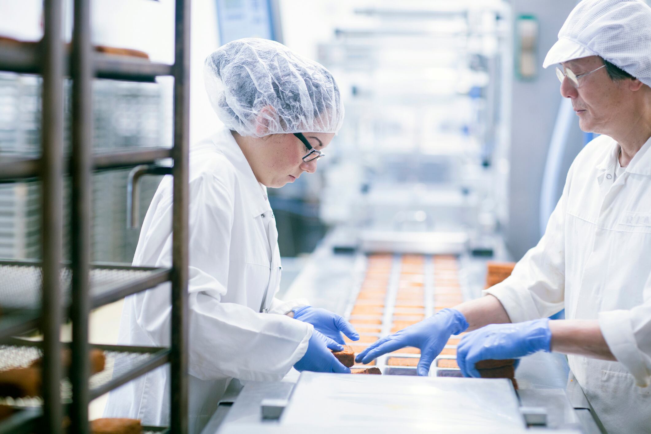 Male and female factory workers on the line dressed in PPE