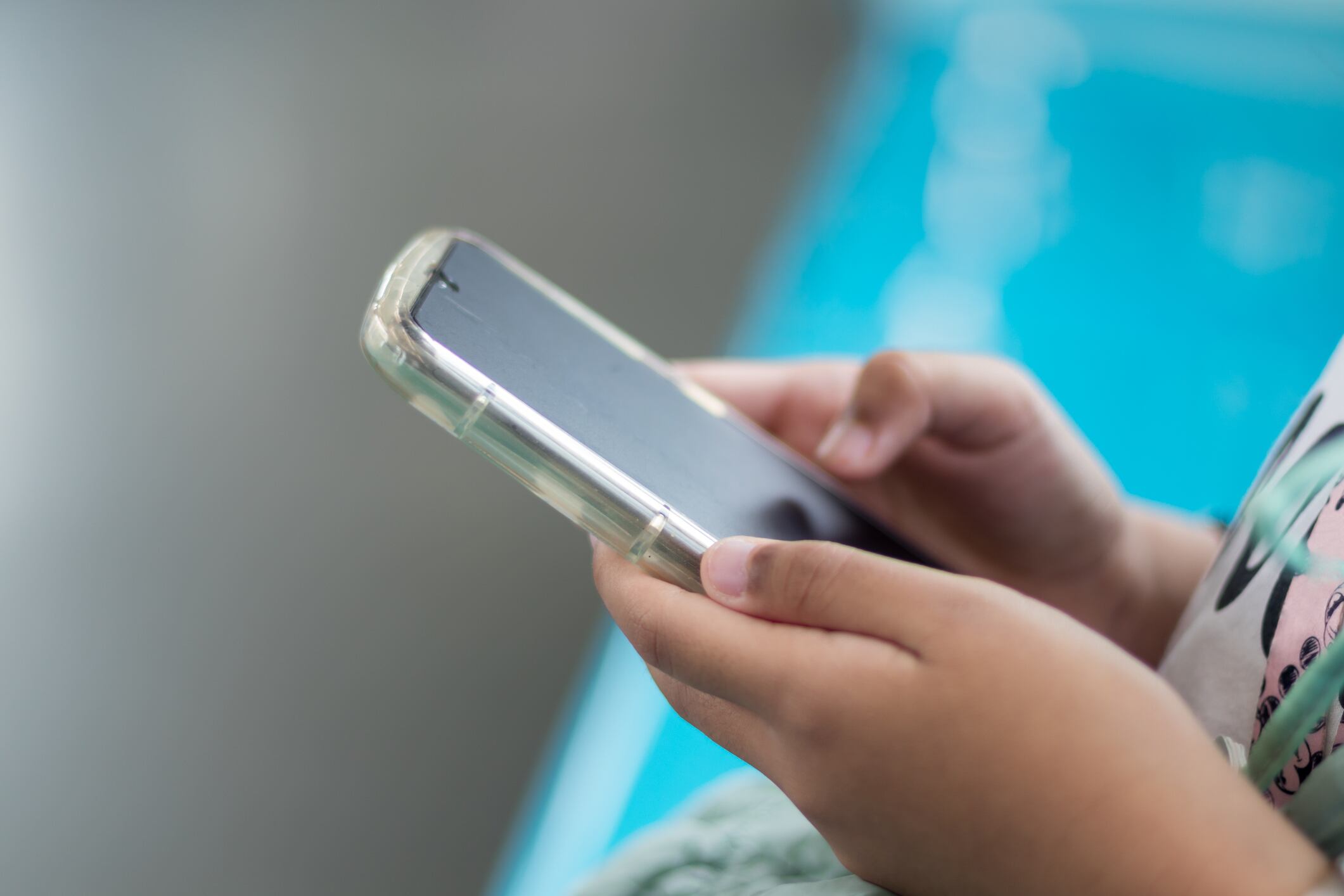 Close up view of a little girl's hand using a smartphone in public transportation.