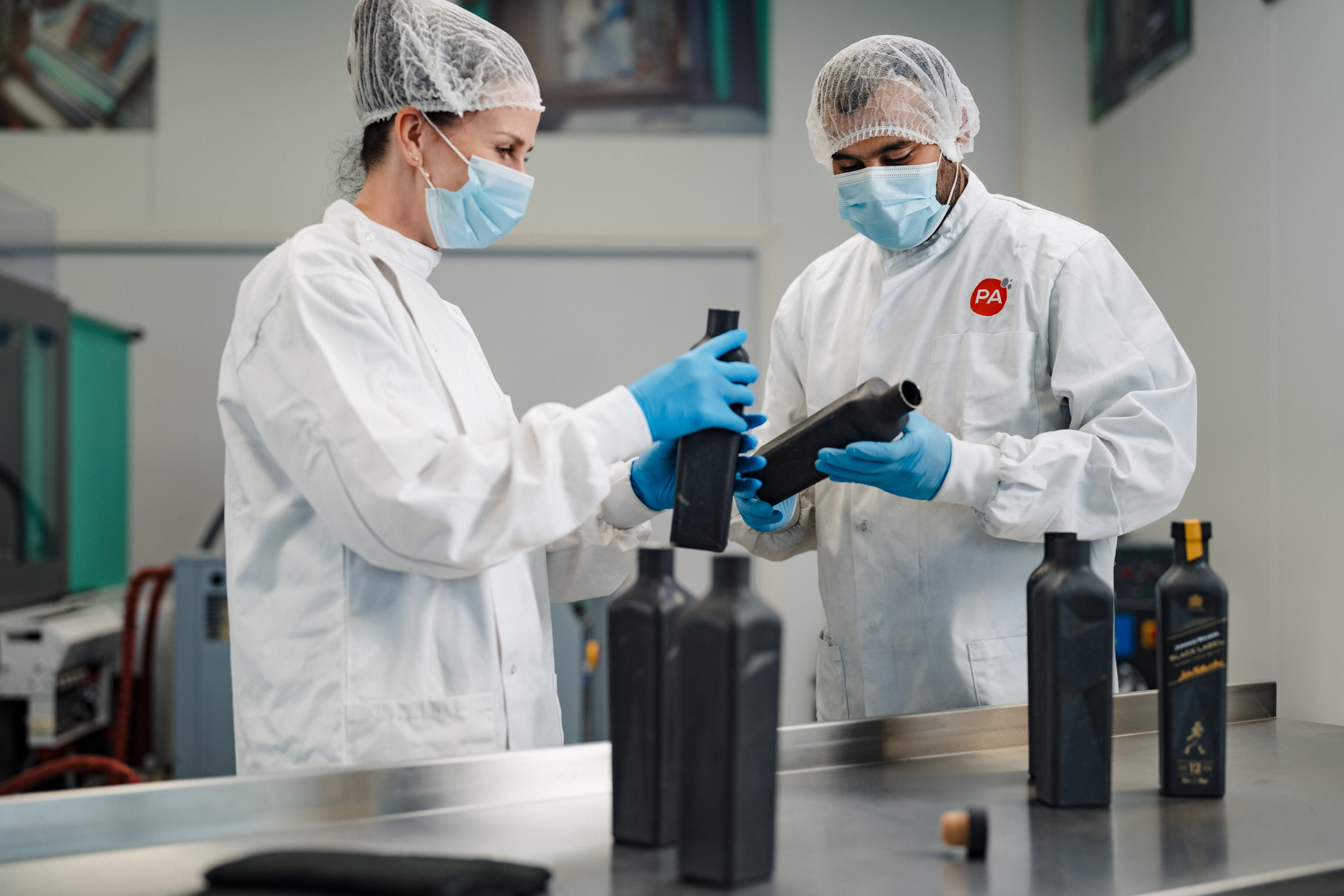 Two people in PPE with bottles on table