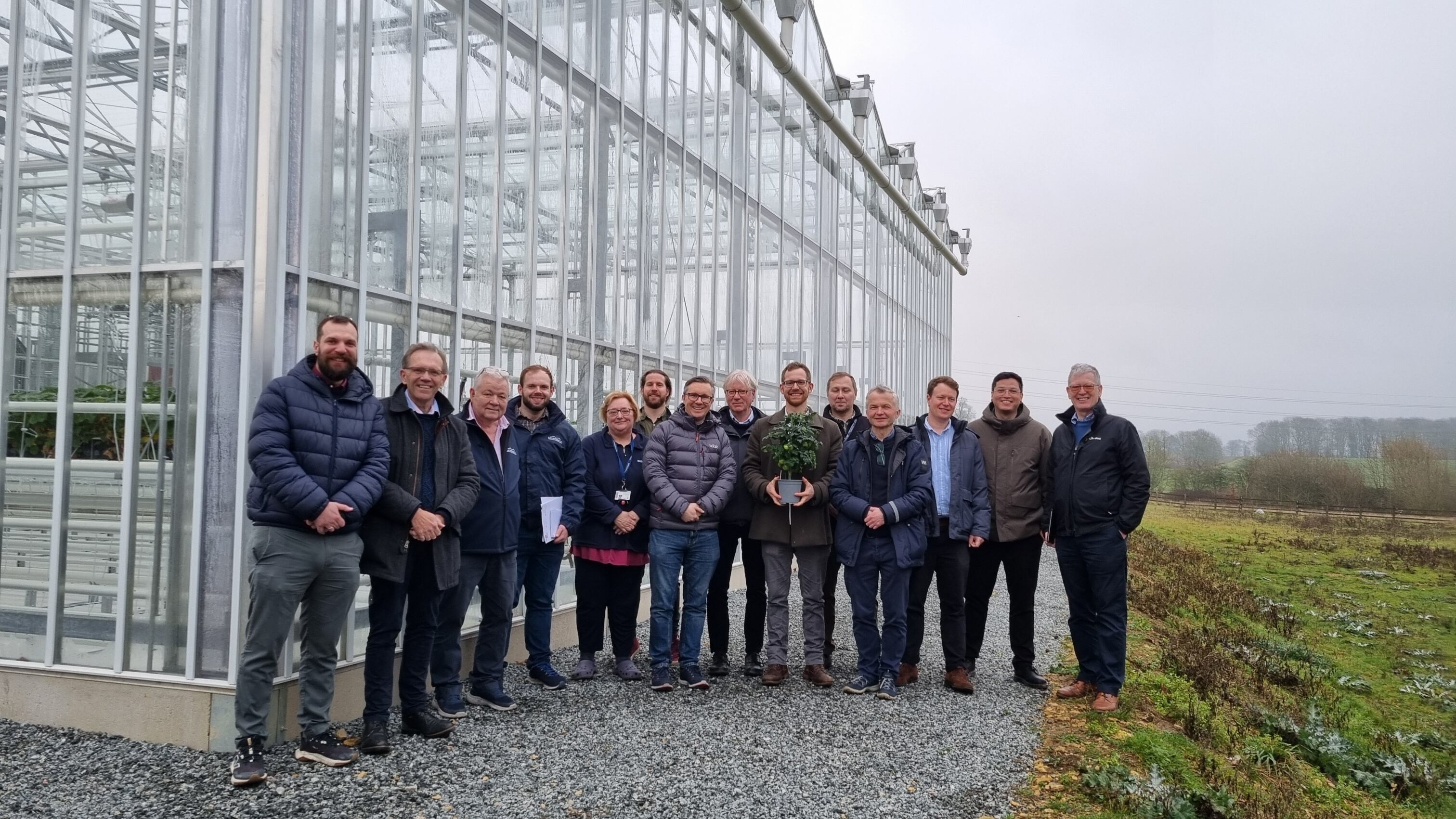 A group of people standing outside a greenhouse.