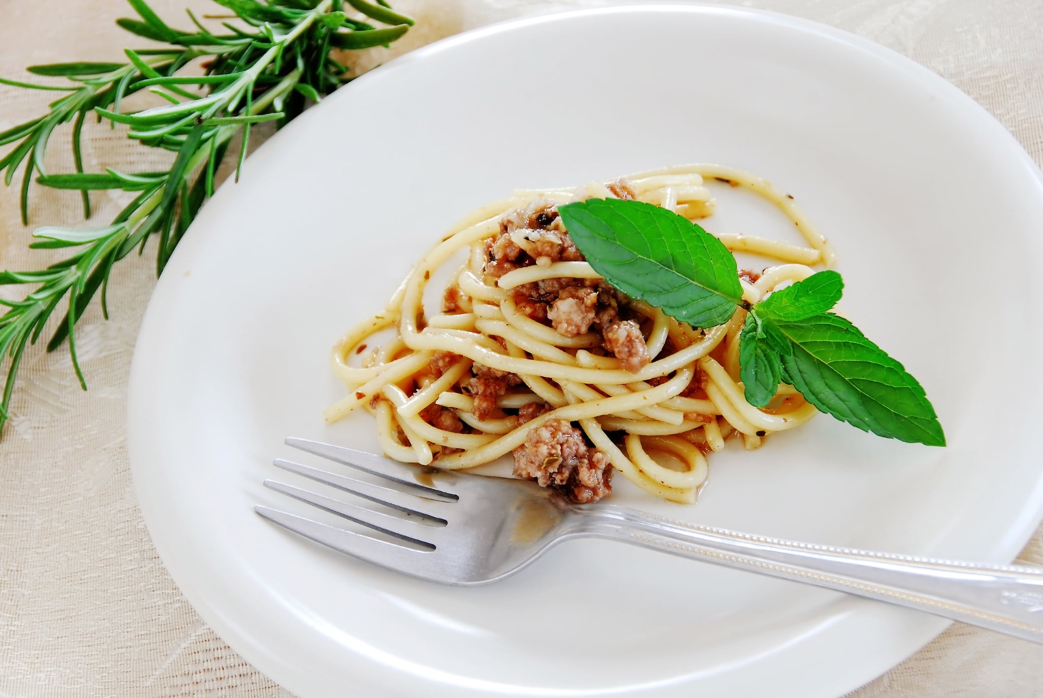 small portion of spaghetti mixed with minced meat served on white plate