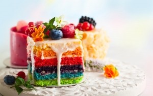 Various slices of rainbow cakes on a white tray_shutterstock_1007816050